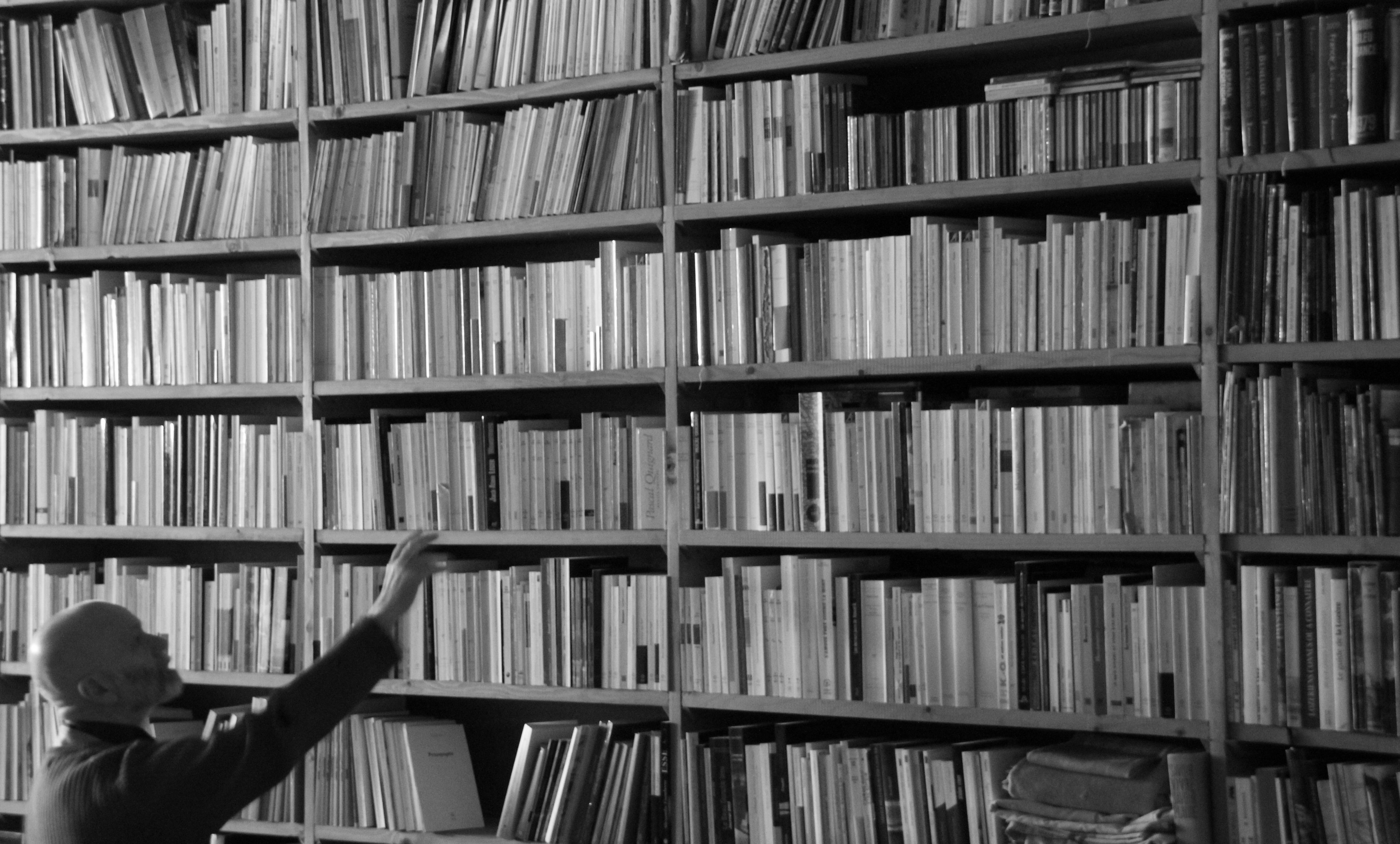 un homme au pied d'une large bibliothèque