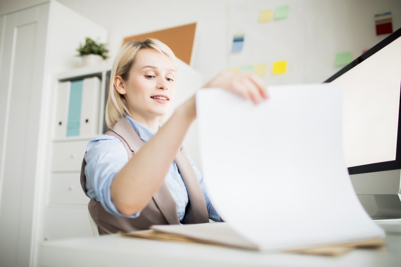 La copie fiable est le meilleur moyen de réduire l'usage du papier en milieu professionnel. (Freepik/seventyfour) Secretaire-positive-visualisation-papiers-bureau