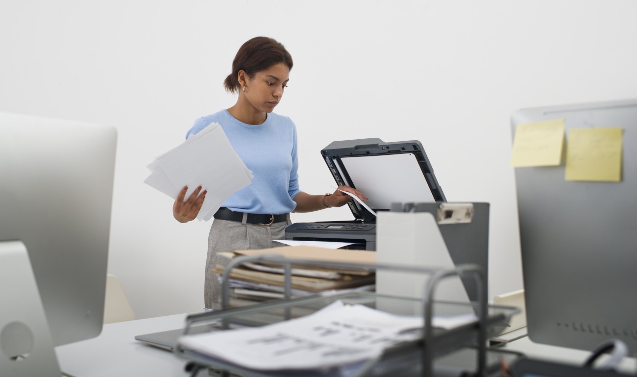 Faire appel à un prestataire certifié pour externaliser ses processus de numérisation est le meilleur moyen de se conformer aux réglementations. (Freepik) scanner-femme-travail-documents-imprimante