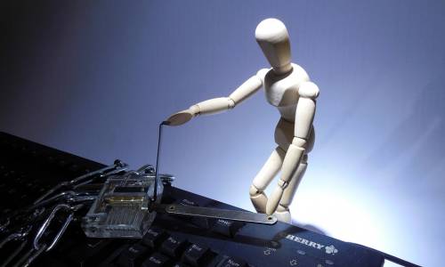 un bonhomme en bois tente d'ouvrir le cadenas qui enferme un clavier d'ordinateur