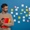 Résultats d'une enquête exclusive, témoignage d'une entreprise et conseils d'experts seront au cœur du Focus de la Rédaction du 18 septembre dédié à la gestion des connaissances. (Freepik/wayhomestudio) un-homme-non-rase-concentre-prend-du-cafe-se-detourne-sur-un-mur-bleu-avec-des-notes-colorees-adhesives-beaucoup-de-travail-et-de-taches